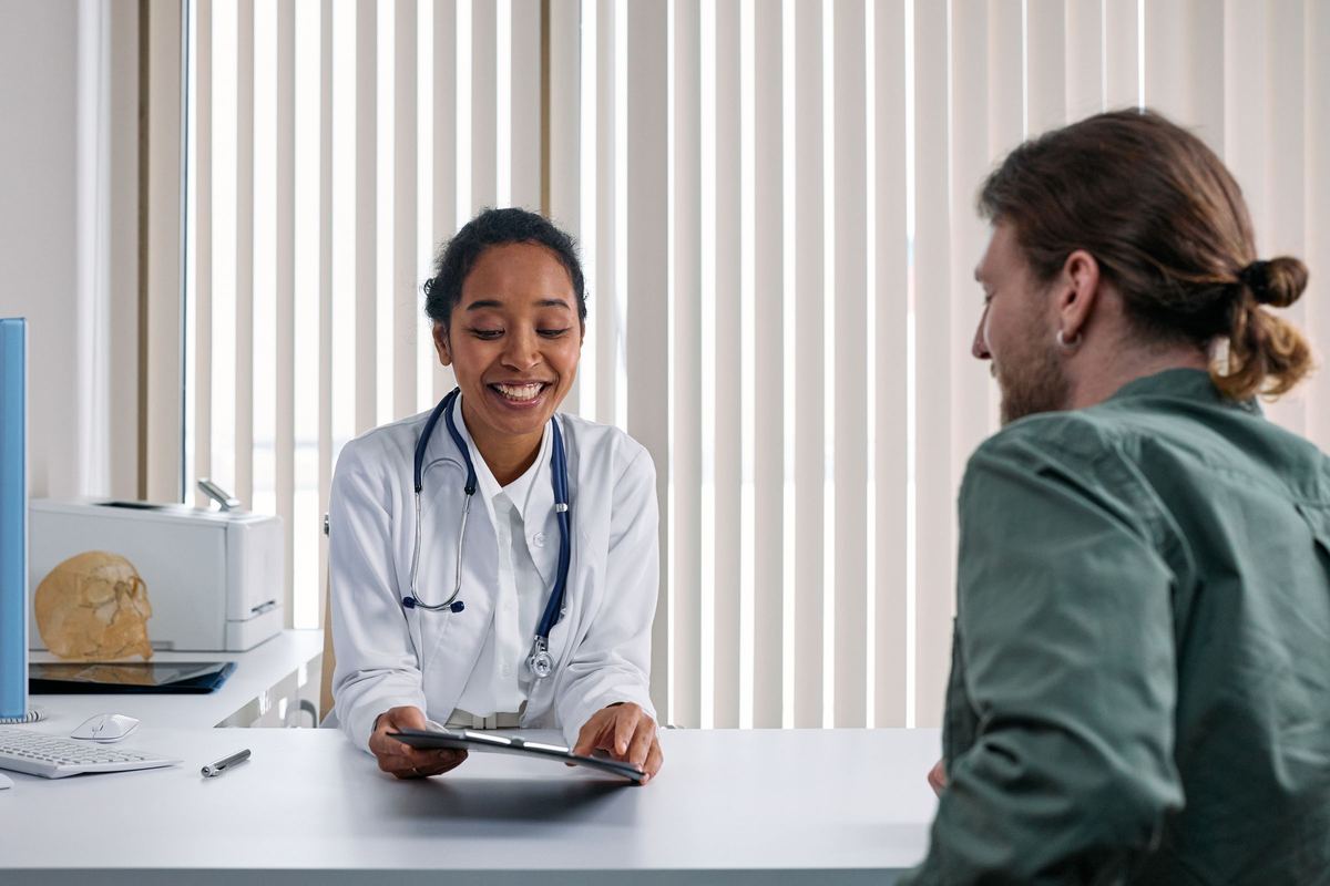 Physician smiling while talking with a patient across a desk