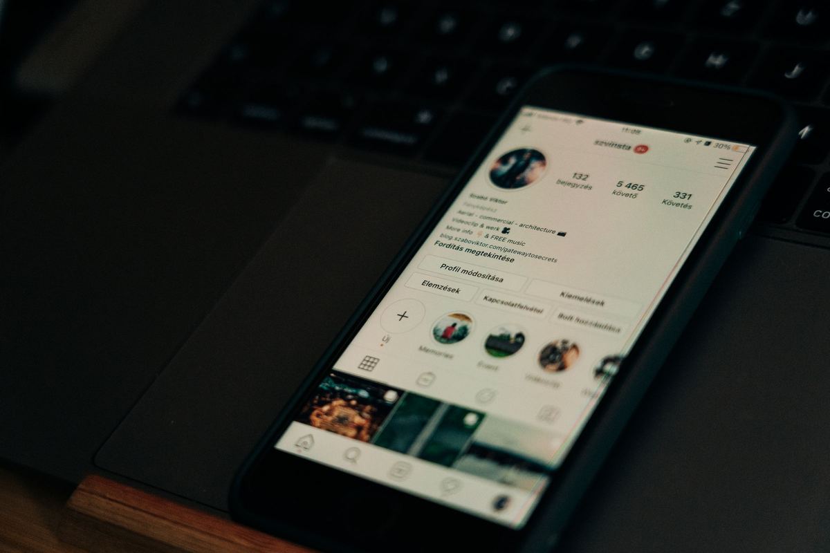 Smartphone showing a social media profile next to a laptop